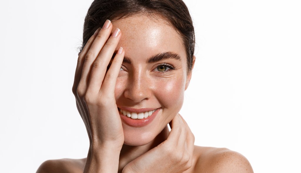 Hermosa joven con piel limpia y perfecta. Retrato de modelo de belleza con maquillaje natural y tocando su cara.